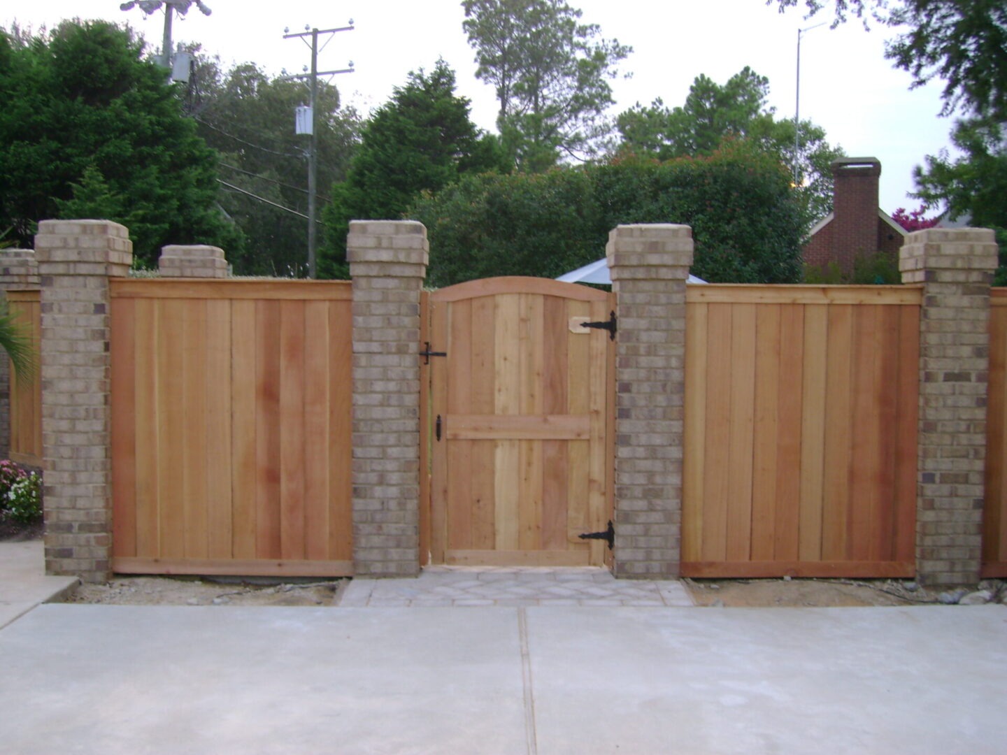 A wooden gate with brick pillars and stone posts.