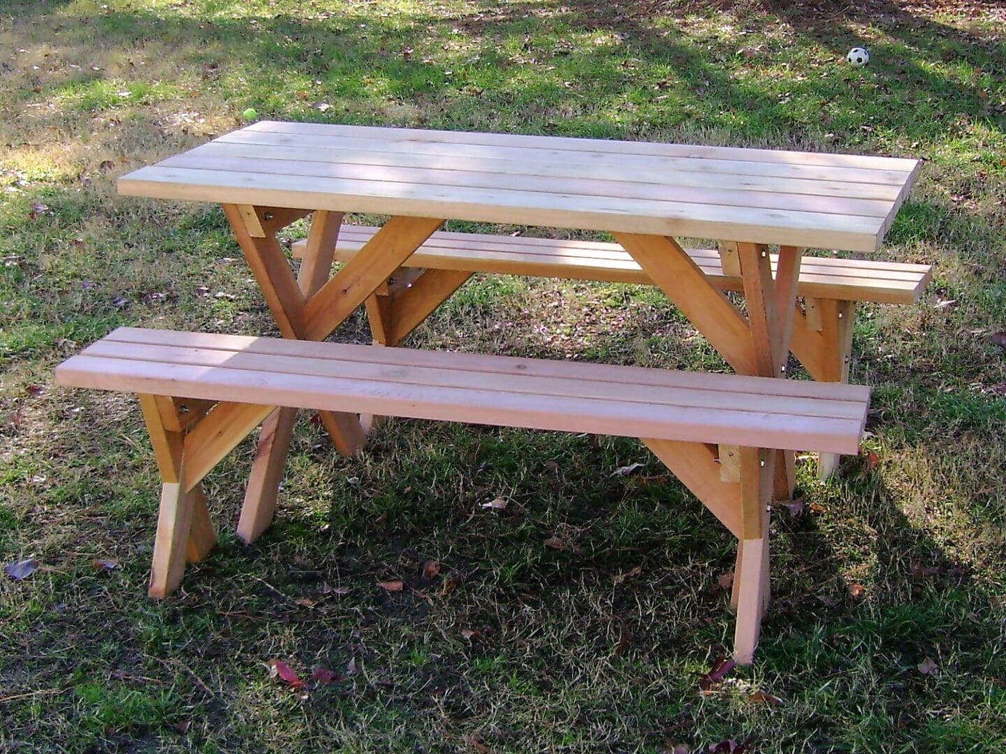 A wooden picnic table and bench in the grass.