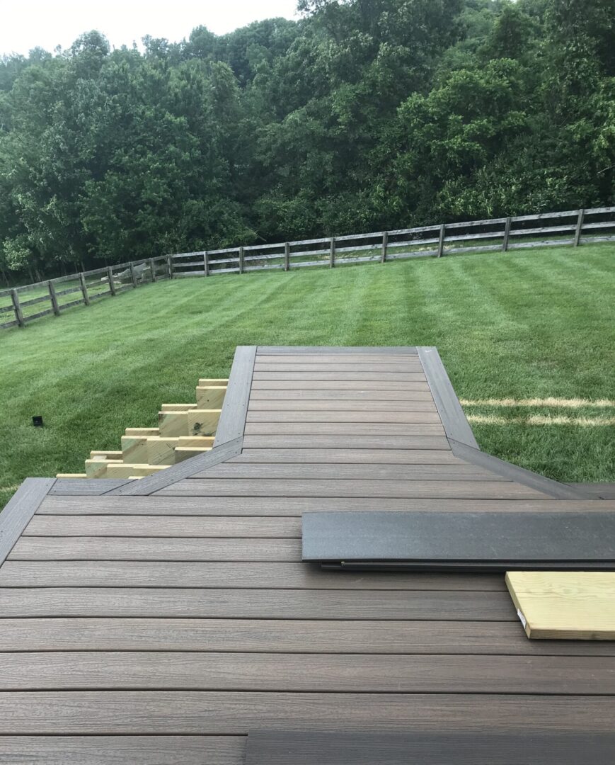 A wooden deck with grass and trees in the background.