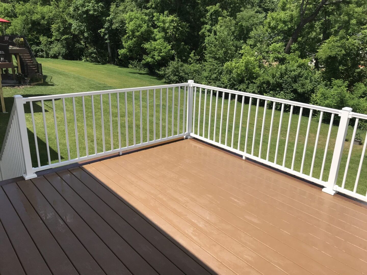 A deck with white railing and brown wood.
