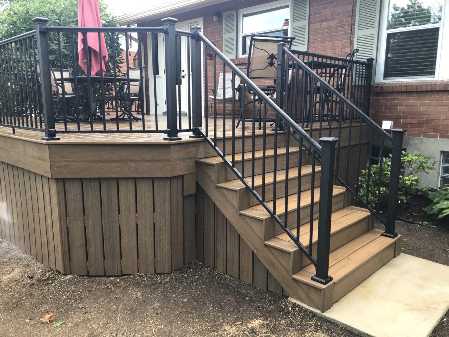 A deck with stairs and railing in the middle of it