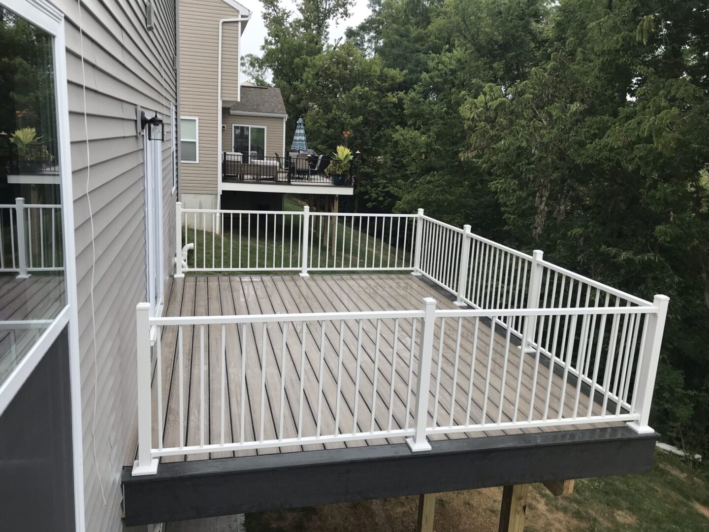 A deck with white railing and black posts.