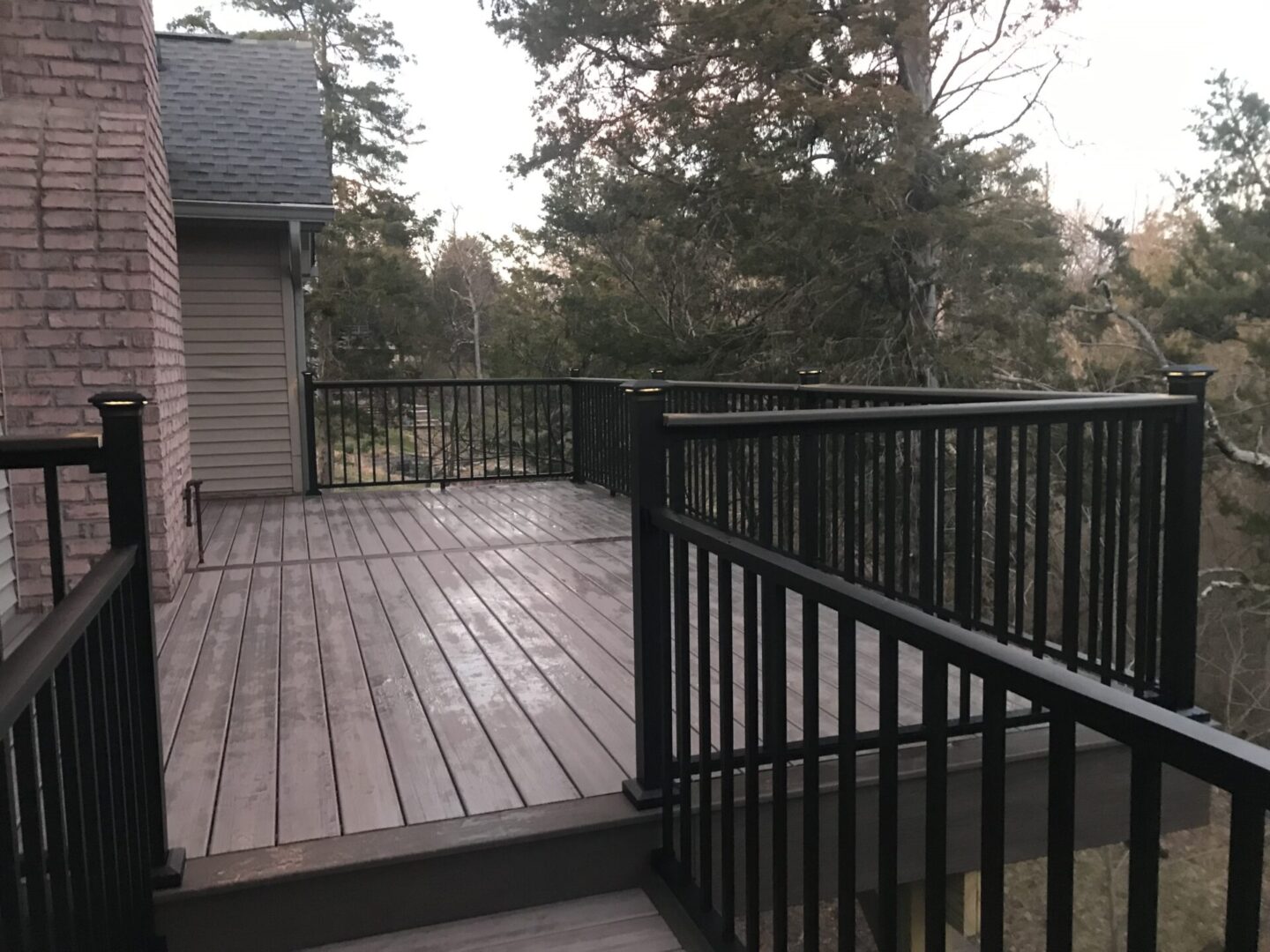 A deck with railing and steps in the middle of it.