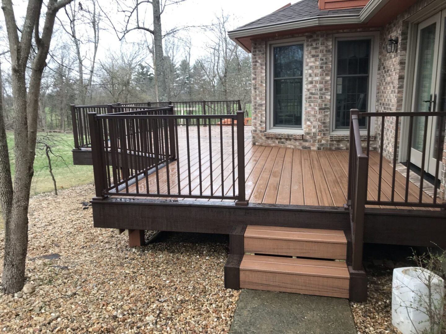 A deck with steps and railing in the middle of it.