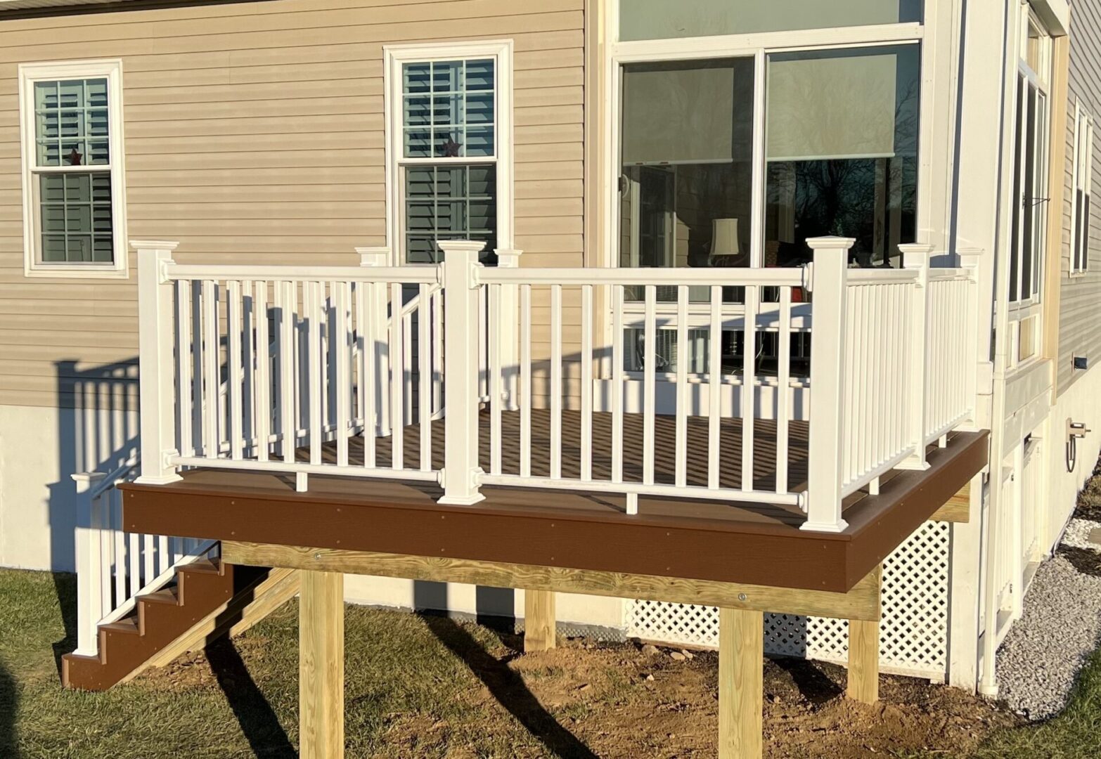 A deck with a bench and railing in the back yard.