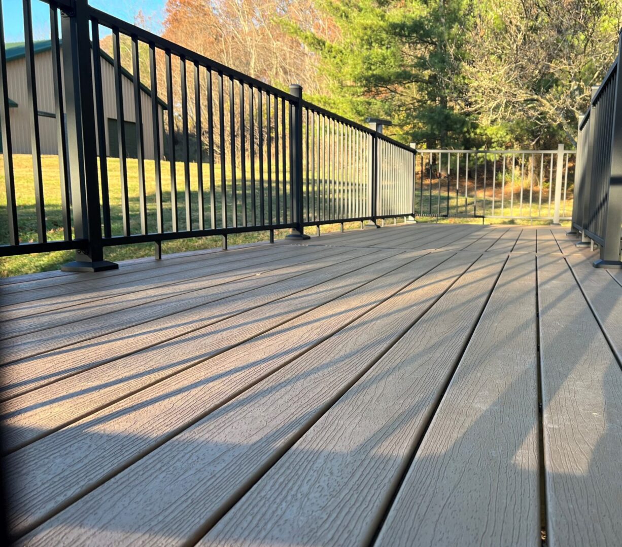 A deck with a railing and trees in the background.