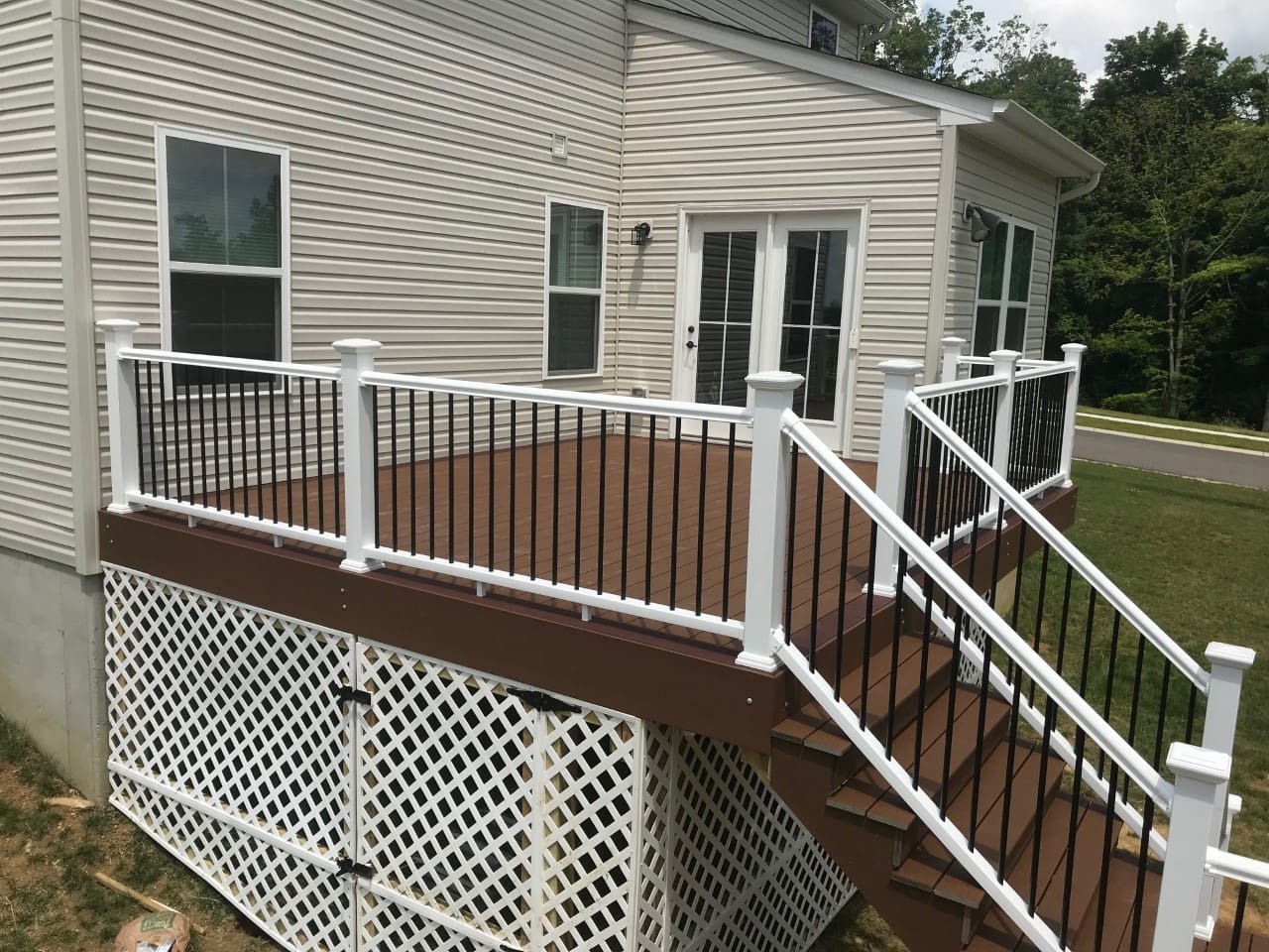 A deck with stairs and railing in the middle of it.