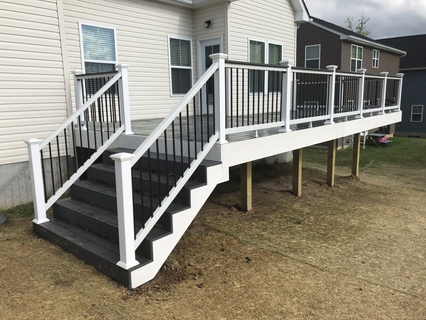 A porch with steps and railing in the middle of it.