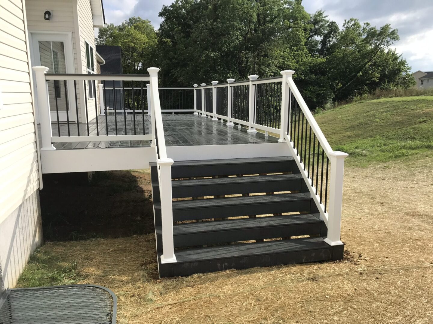 A deck with stairs and railing in the middle of it.