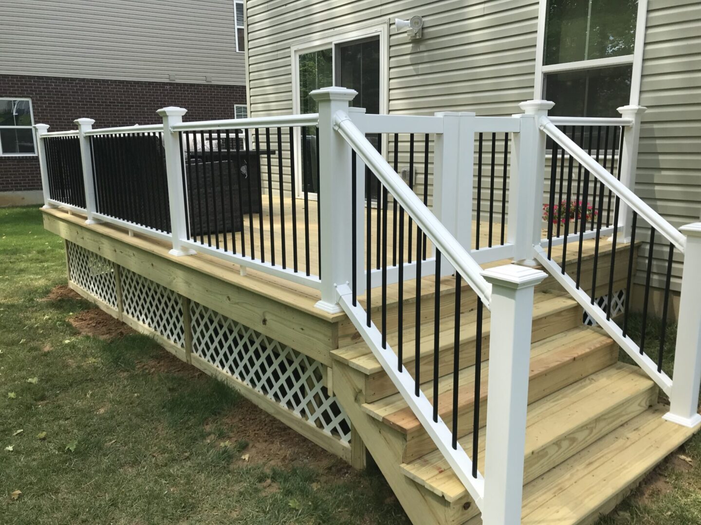 A deck with stairs and railing in the back yard.