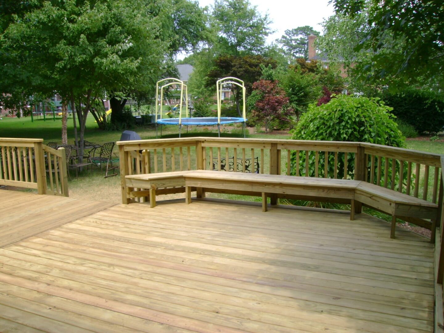 A wooden deck with benches and trees in the background.